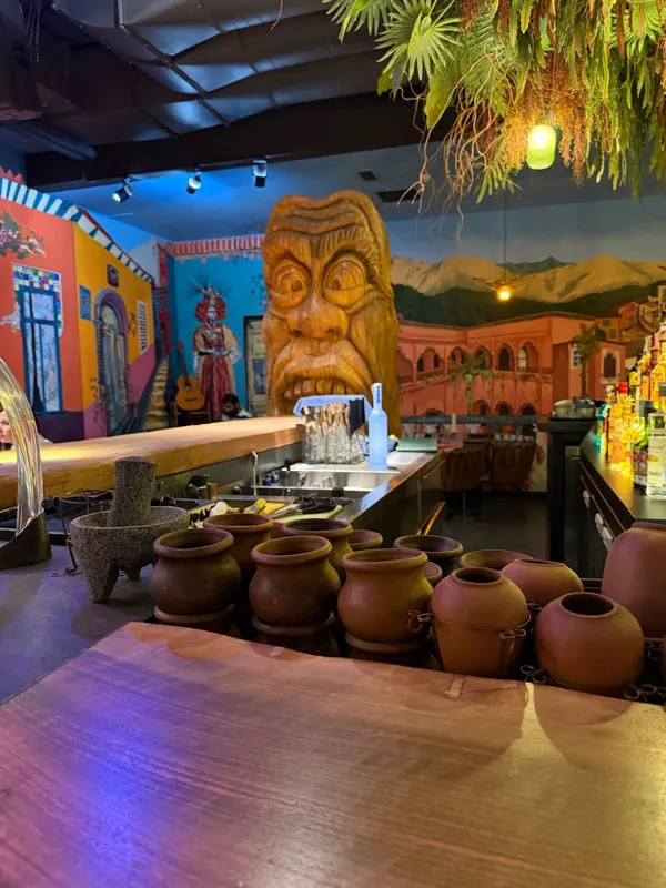 The bar: a giant carved wooden mask, clay pots and a painted Mexican street