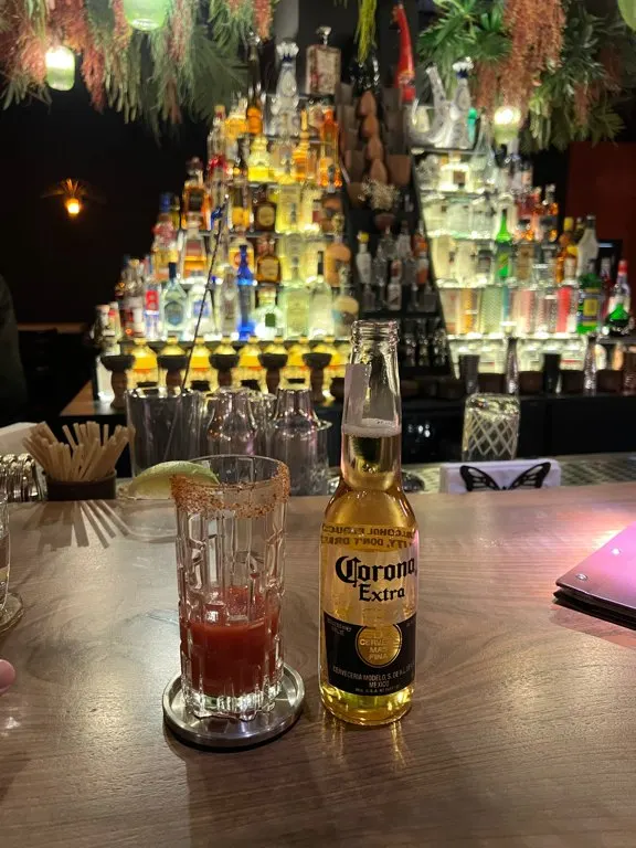 Tequila pyramid behind the bar, a Corona and a cocktail